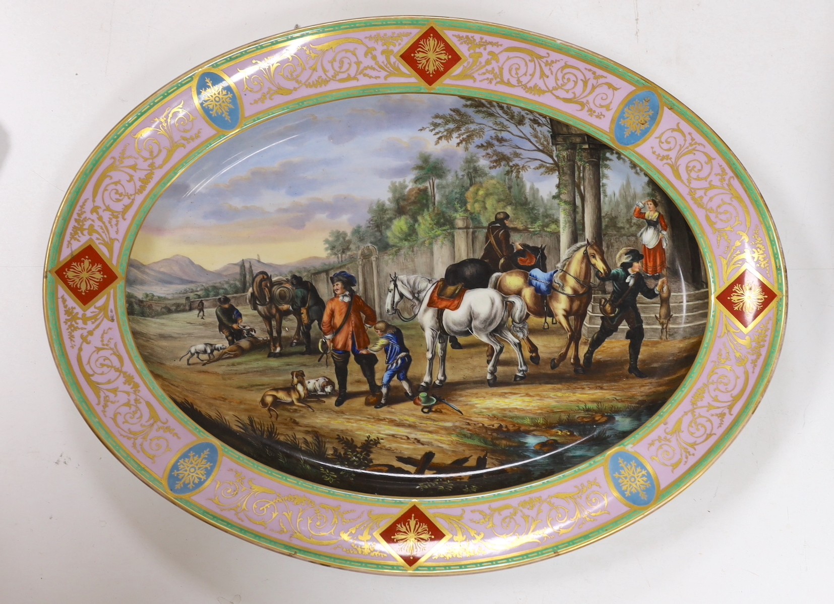 A large Vienna style porcelain oval dish, late 19th century, painted with huntsmen and horses in a landscape, 52cm long